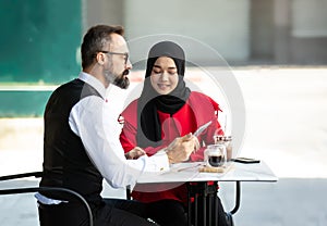 Two business people sitting at cafe working on new project.