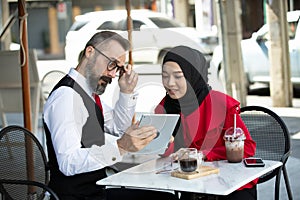 Two business people sitting at cafe working on new project.