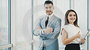 Two business people are smiling for camera with thier thumb fingers up, isolated on white panoramic background. Close up