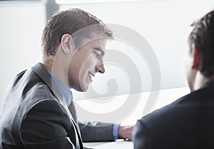 Two business people smiling and looking down at a business meeting