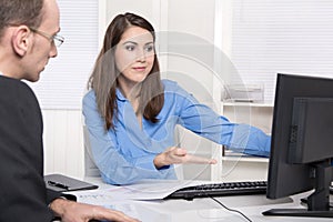 Two business people talking together at desk - adviser and customer