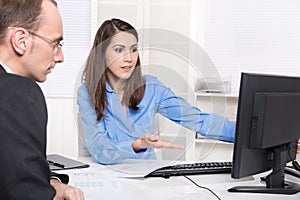 Two business people talking together at desk - adviser and customer