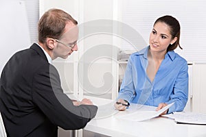 Two business people talking together at desk - adviser and customer