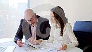 Two Business people working with tablet. They discussing business ideas sitting on the chairs in the modern light office