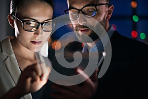 Two business people working on tablet at night