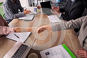 Two business teams sitting at both sides of table in meeting room.