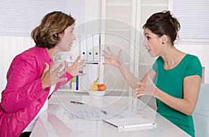 Two business woman disputing in the office having disagreement.