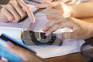 Two business woman hand counting on calculator and holding credit card ,debt collection and shopping online concept