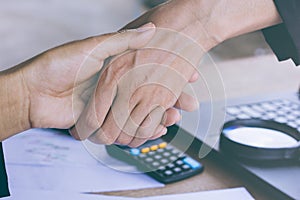 Two business woman handshake after working together and agree on their project at office with some financial paper graph