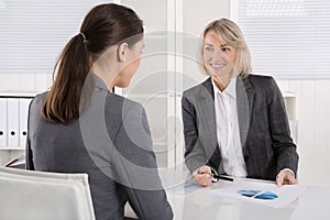 Two business woman sitting at desk: customer and adviser talking