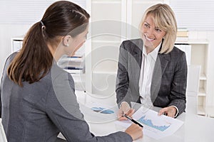 Two business woman sitting at desk: customer and adviser talking