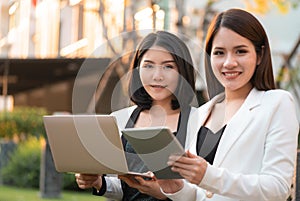 Two business woman is working together in a park outd