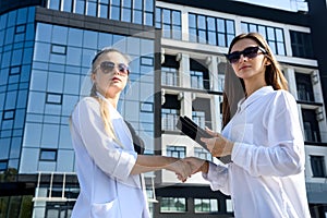 Two business women discussing some questions outside office building