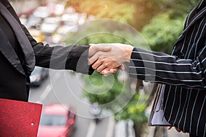 Two business women hand shake at outdoors with traffic background, Business and contact agreement concept
