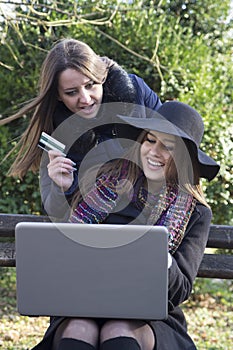 Two business women in the park to buy a laptop