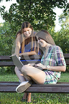 Two business women in the park to buy a laptop