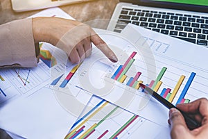 Two business women review and analyzing income charts and graphs with modern laptop computer. Close up businesswomen finger