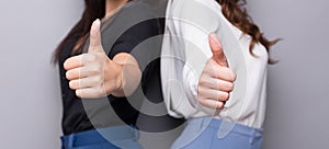 Two business women showing thumbs up gesture
