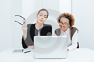 Two business women sitting and working with laptop together