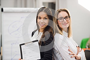 Two business women standing at office in front of flip chart