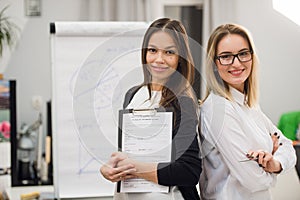 Two business women standing at office in front of flip chart