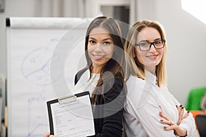 Two business women standing at office in front of flip chart