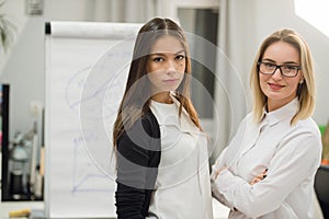 Two business women standing at office in front of flip chart