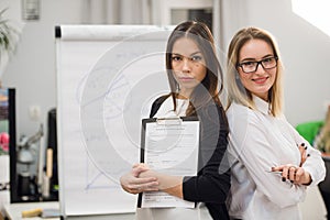 Two business women standing at office in front of flip chart