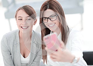 Two business women taking selfies in the office