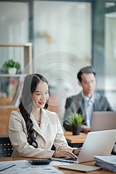 Two business workers smiling happy working sitting on desk at the office.