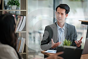 Two business workers smiling happy working sitting on desk at the office.