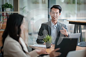 Two business workers smiling happy working sitting on desk at the office.