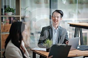 Two business workers smiling happy working sitting on desk at the office.