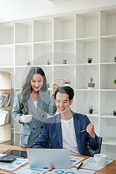 Two business workers smiling happy working sitting on desk at the office.