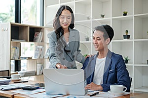 Two business workers smiling happy working sitting on desk at the office.