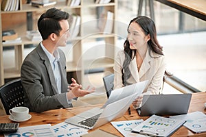 Two business workers smiling happy working sitting on desk at the office.