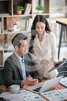 Two business workers smiling happy working sitting on desk at the office.