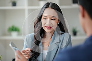 Two business workers smiling happy working sitting on desk at the office.