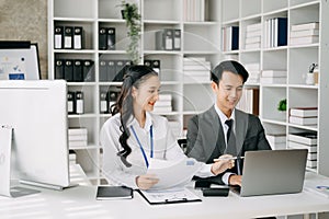 Two business workers talking on the smartphone and using laptop at the office