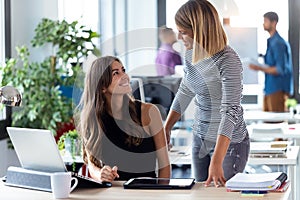 Two business young women working together with digital tablet in the modern startup office