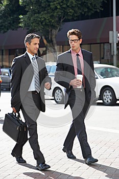 Two Businessman Chatting Whilst Crossing Street