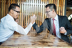 Two businessman expressed a serious expression and fighting by used arm wrestling on wood table. photo