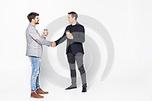 Two businessman handshake standing with coffee cup isolated on a white background