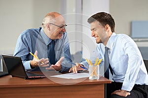 Two businessman with laptop, office as background