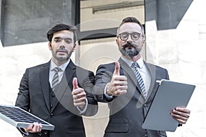 Two businessmans trumps up and holding power solar cell and laptops computer with smile confident on site new project power photo