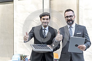 Businessman trumps up and holding power solar cell and laptops computer with smile confident on site new project power photo