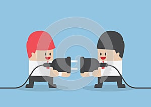Two businessman trying to connect electric plug together