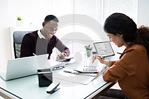 Two Businessman Using Calculator At Workplace