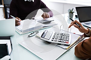 Two Businessman Using Calculator At Workplace