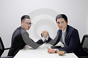 Two businessmen competing arm wrestling in office